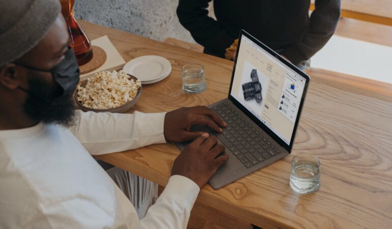 Person sitting on a table on Surface laptop wearing a mask